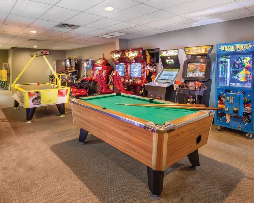 AN INDOOR RECREATIONAL AREA WITH POOL TABLE AIR HOCKEY TABLE AND ARCADE GAMES.
