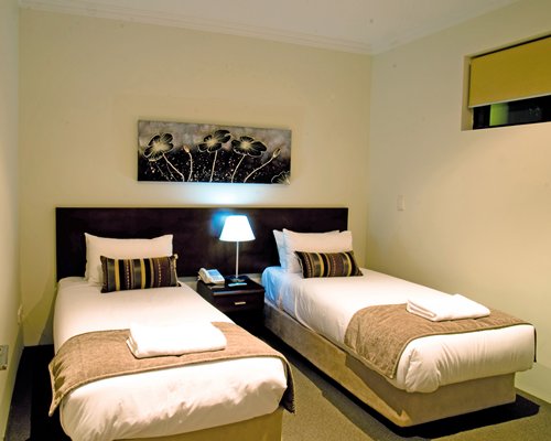 A well furnished bedroom with twin beds and lamp.