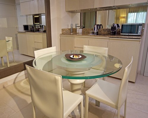 An open plan kitchen with glass top dining table.