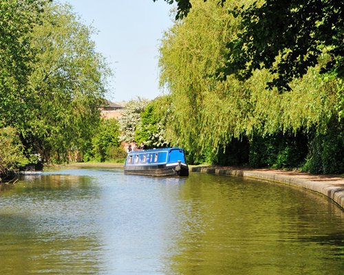 A canal boat in the waterfront surrounded by wooded area.