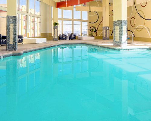 An indoor swimming pool with patio furniture and an outside view.