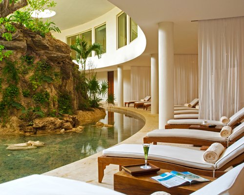 An outdoor pool with chaise lounge chairs and landscaping alongside the resort.