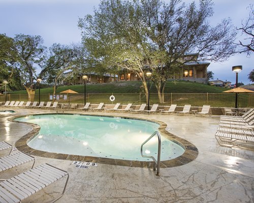 Outdoor swimming pool and hot tub with chaise lounge chairs and dining with sunshades.