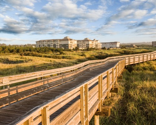 A WOODEN PIER LEADING TO THE RESORT.
