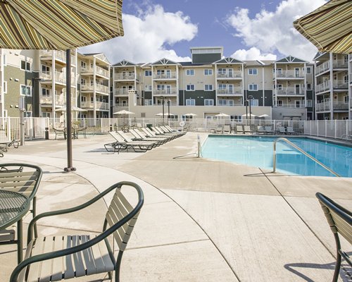 View of multiple unit balconies alongside swimming pool with chaise lounge chairs.