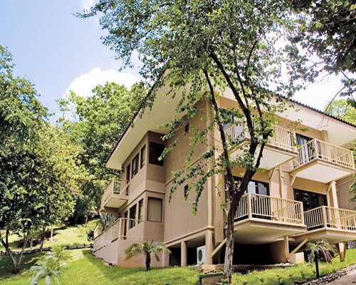 Exterior view of a unit with multiple balconies at a wooded area.