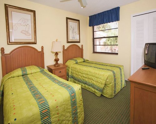 A well furnished bedroom with two twin beds a television and outside view.