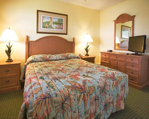 A well furnished bedroom with a queen bed and a television.