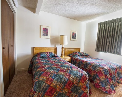 A well furnished bedroom with two twin beds and lamp.