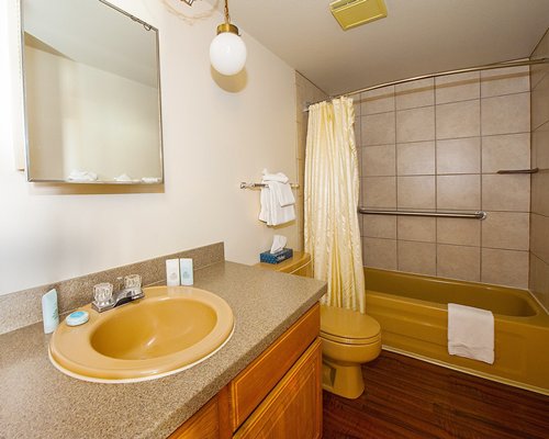 A bathroom with a bathtub shower and single sink vanity.