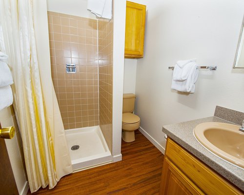A bathroom with single sink vanity and a stand up shower.
