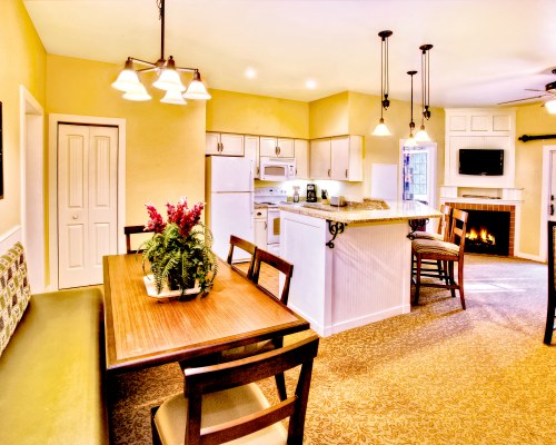 AN OPEN PLAN DINING AND KITCHEN AREA WITH A BREAKFAST BAR TELEVISION AND FIRE IN THE FIREPLACE.