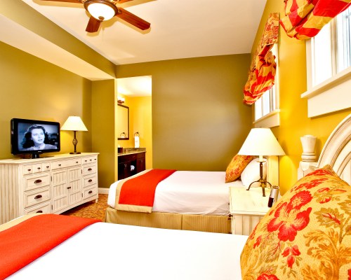 A WELL FURNISHED BEDROOM WITH TWO BEDS AND A TELEVISION.