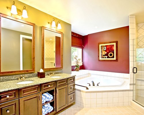 A bathroom with bathtub shower and double sink vanity.