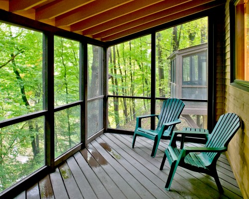 BALCONY WITH PATIO CHAIRS AND VIEW OF A WOODED AREA.