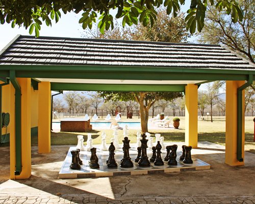 A lawn chess set alongside swimming pool with chaise lounge chairs.