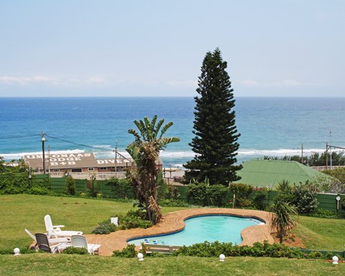 Outdoor swimming pool with chaise lounge chairs alongside the ocean.