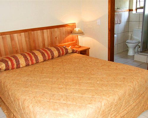 A well furnished bedroom with an enclosed bathroom.