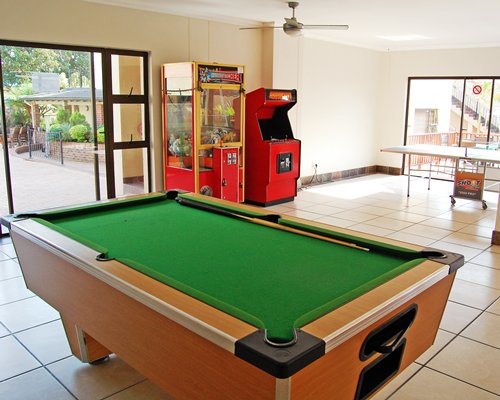 An indoor recreation room with ping pong pool table and arcade game.