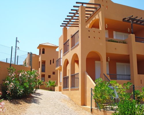An exterior view of multi story resort units with flowering shrubs.