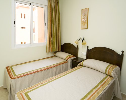 A well furnished bedroom with two beds and outside view.