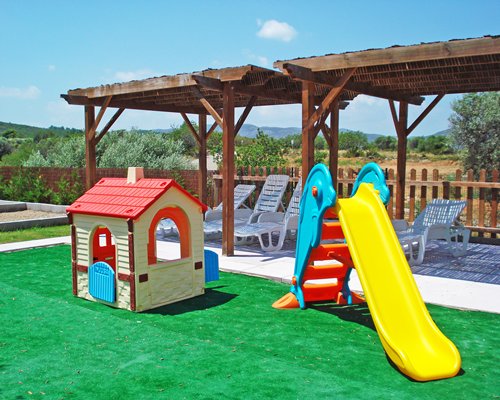 A view of an outdoor playscape alongside chaise lounge chairs with pergolas.