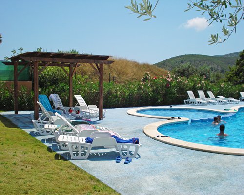 People at an outdoor swimming pool with chaise lounge chairs.
