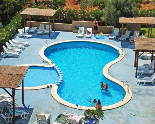 An aerial view of an outdoor swimming pool with chaise lounge chairs and sunshades.