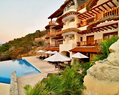 An outdoor swimming pool with chaise lounge chairs and patio furniture alongside resort units.