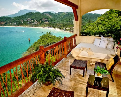 A view of the floor bed and patio furniture in the balcony alongside the ocean.