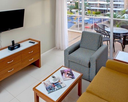 A well furnished living room with a television balcony and patio furniture.