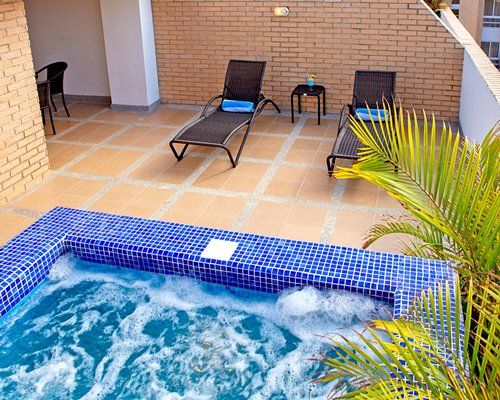 A balcony with a hot tub and chaise lounge chairs.