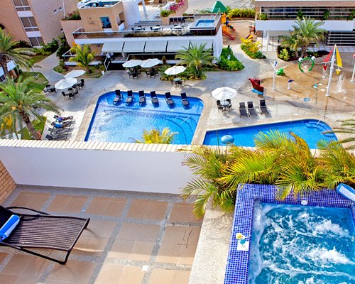 An outdoor swimming pool and hot tub with chaise lounge chairs.