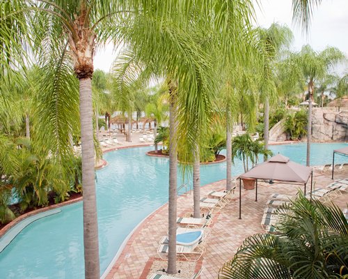 An outdoor swimming pool with chaise lounge chairs and trees.