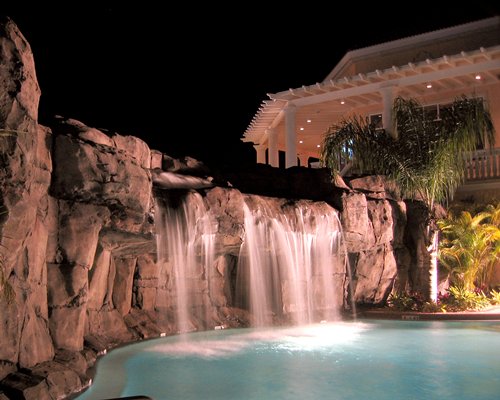 An outdoor grotto pool alongside multi story resort units at night.