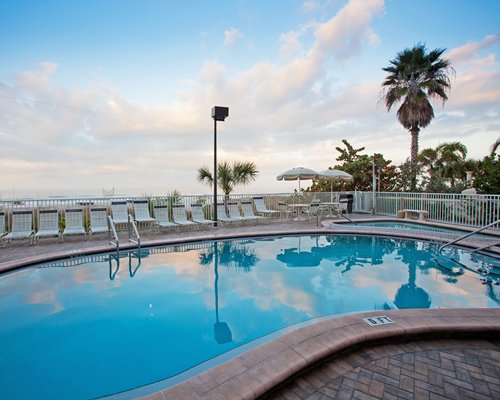 An outdoor swimming pool with chaise lounge chairs and sunshades.