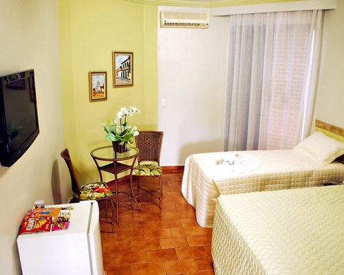 A well furnished bedroom with two twin beds and television.