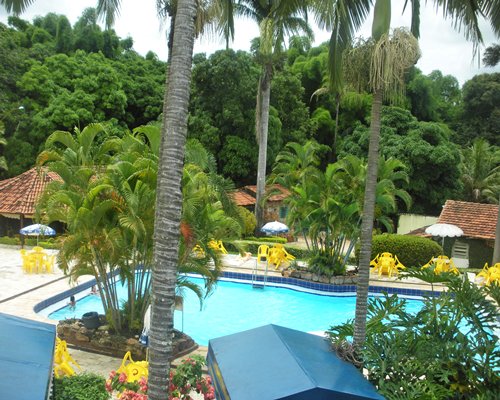 Outdoor swimming pool with patio chairs and sunshades.