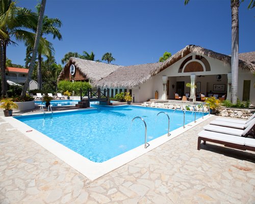 An outdoor swimming pool with chaise lounge chairs alongside resort unit.