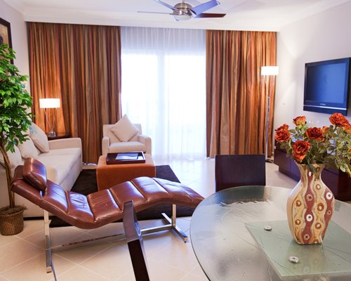 A well furnished living room with a television chaise lounge chair and outside view.