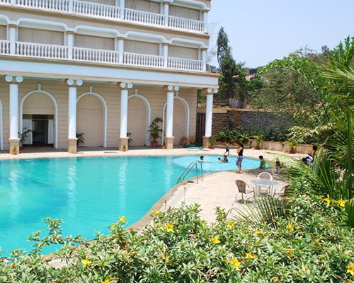 An outdoor swimming pool alongside resort units and trees.