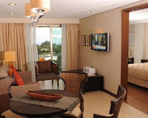 A well furnished living room with a television and dining area alongside bedroom.