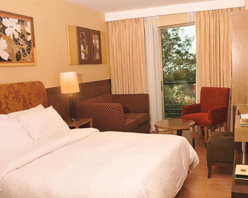 A well furnished bedroom with patio furniture and balcony.