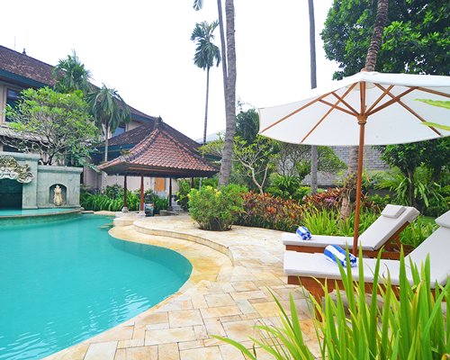 An outdoor pool with chaise lounge chairs and umbrellas alongside the resort.
