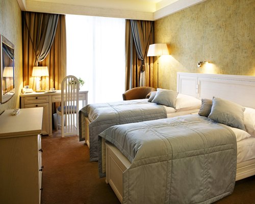 A well furnished bedroom with two beds and a television.