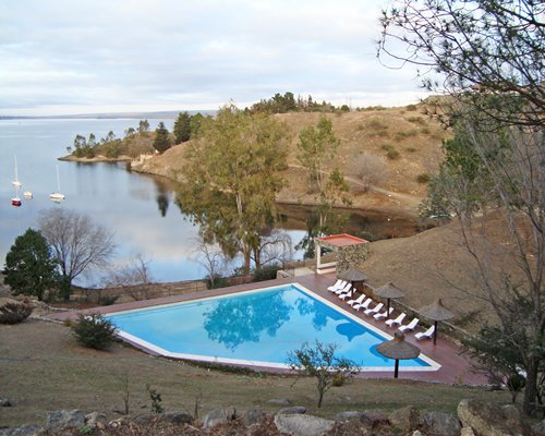 An outdoor swimming pool with chaise lounge chairs alongside the lake.