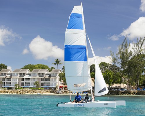 A sailboat on the ocean alongside resort property.