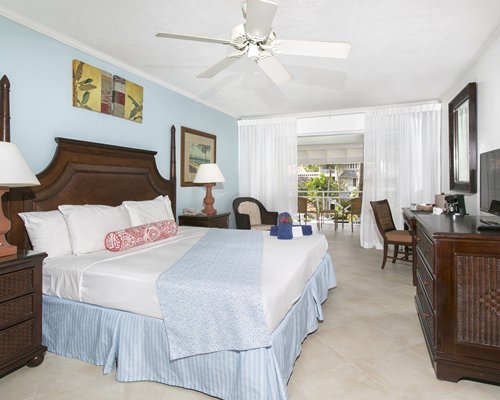 A well furnished bedroom with a television and balcony.