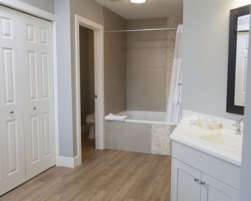 A bathroom with a bathtub shower and single sink vanity.