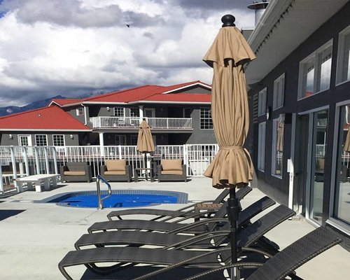 An outdoor pool with chaise lounge chairs and sunshades alongside the resort.
